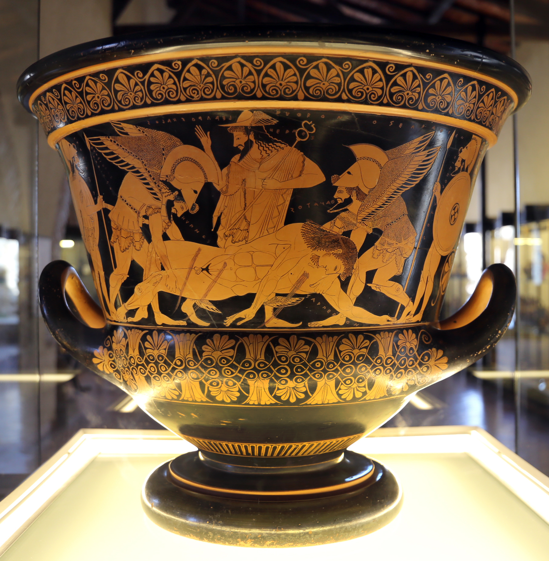 The Euphronios krater in its case, the principal frieze showing the body of Sarpedon lifted by Sleep and Death under the direction of Hermes. Acquired by the Metropolitan in 1972 on its curator's recommendation and returned to Italy; it is now at the Museo Archeologico Nazionale Cerite in Cerveteri.