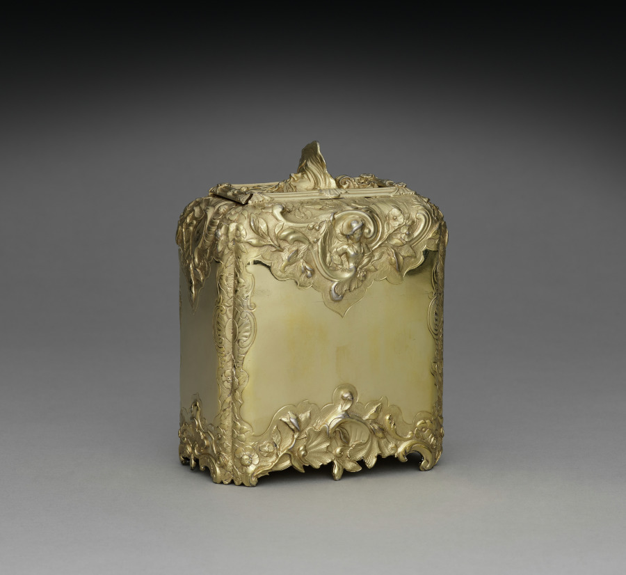 A silver-gilt tea caddy by Paul de Lamerie, hallmarked London 1741-42, 13.4 by 9.6 by 5.8 cm. The front cartouche is deliberately blank: no arms, no crest, no cypher, nothing engraved on it by anybody who owned it. The museum that holds it records the woman it came from as Mrs. Thomas S. Grasselli, and prints her own name, Emilie Schmidt, only inside square brackets in the middle of her husband's.