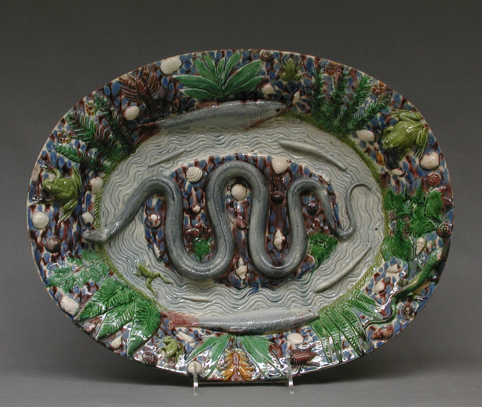 Oval platter in the manner of Bernard Palissy, moulded with a snake coiled across a rippled ground, a lizard, ferns, shells and small crustaceans, the rim crowded with further creatures. The Metropolitan classifies it as Ceramics-Pottery and holds it in the Department of European Sculpture and Decorative Arts, not with the other glazed earthenware in this archive.