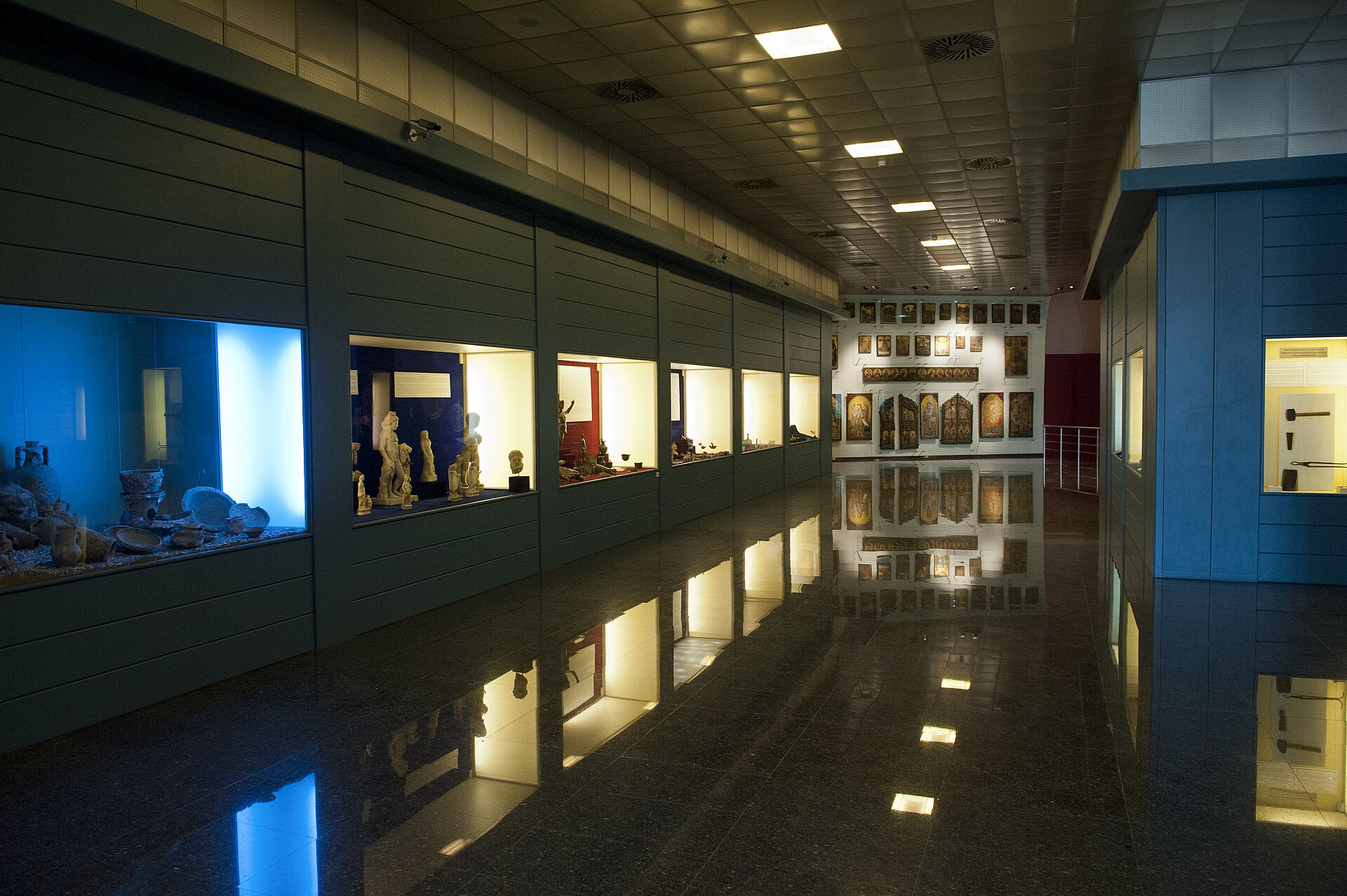 A first-floor display corridor in the 1972 building, wall cases of small finds on one side and a run of framed panels on the far wall