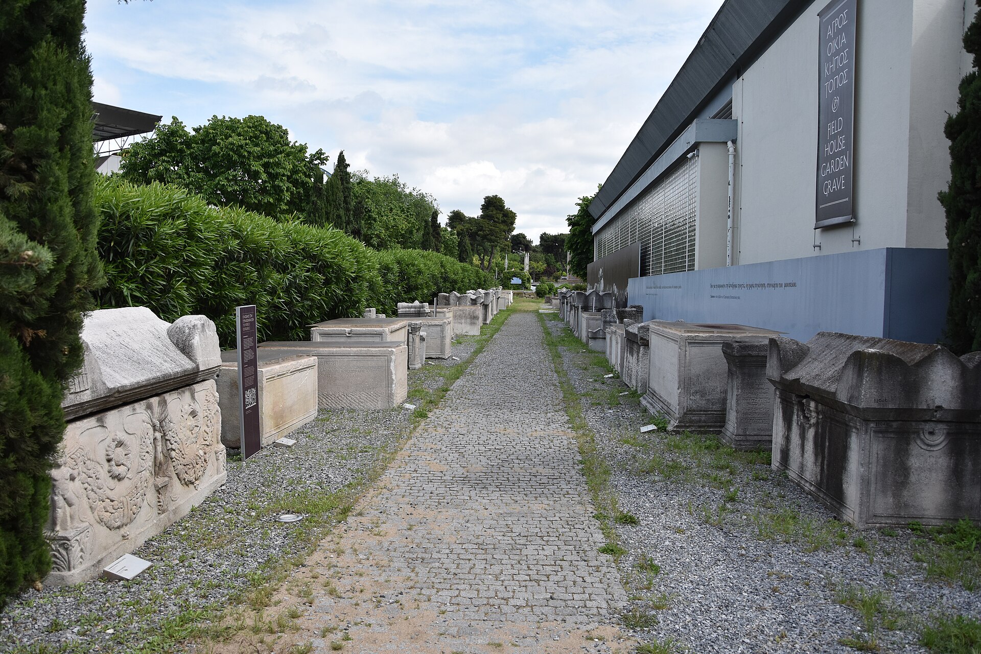 Rows of marble sarcophagi and funerary stelae lined up along a gravel path in the museum's garden
