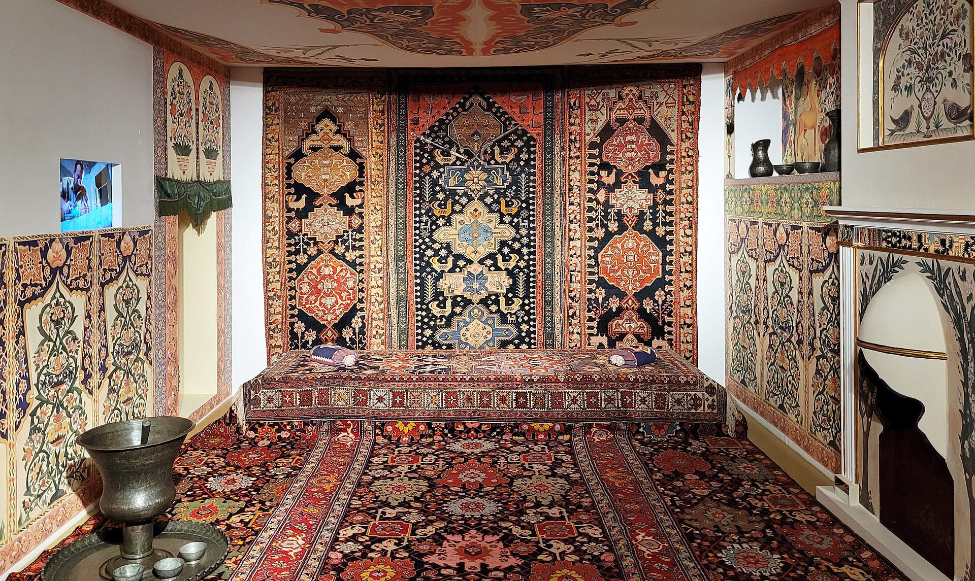 A reconstructed traditional room with carpets covering the floor, walls and ceiling around a low seating platform