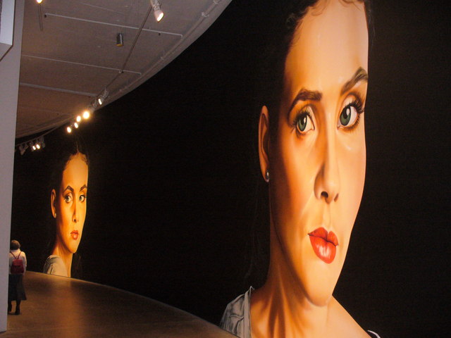 Large curved photographic portraits hung along a curved gallery wall inside the Barbican Art Gallery