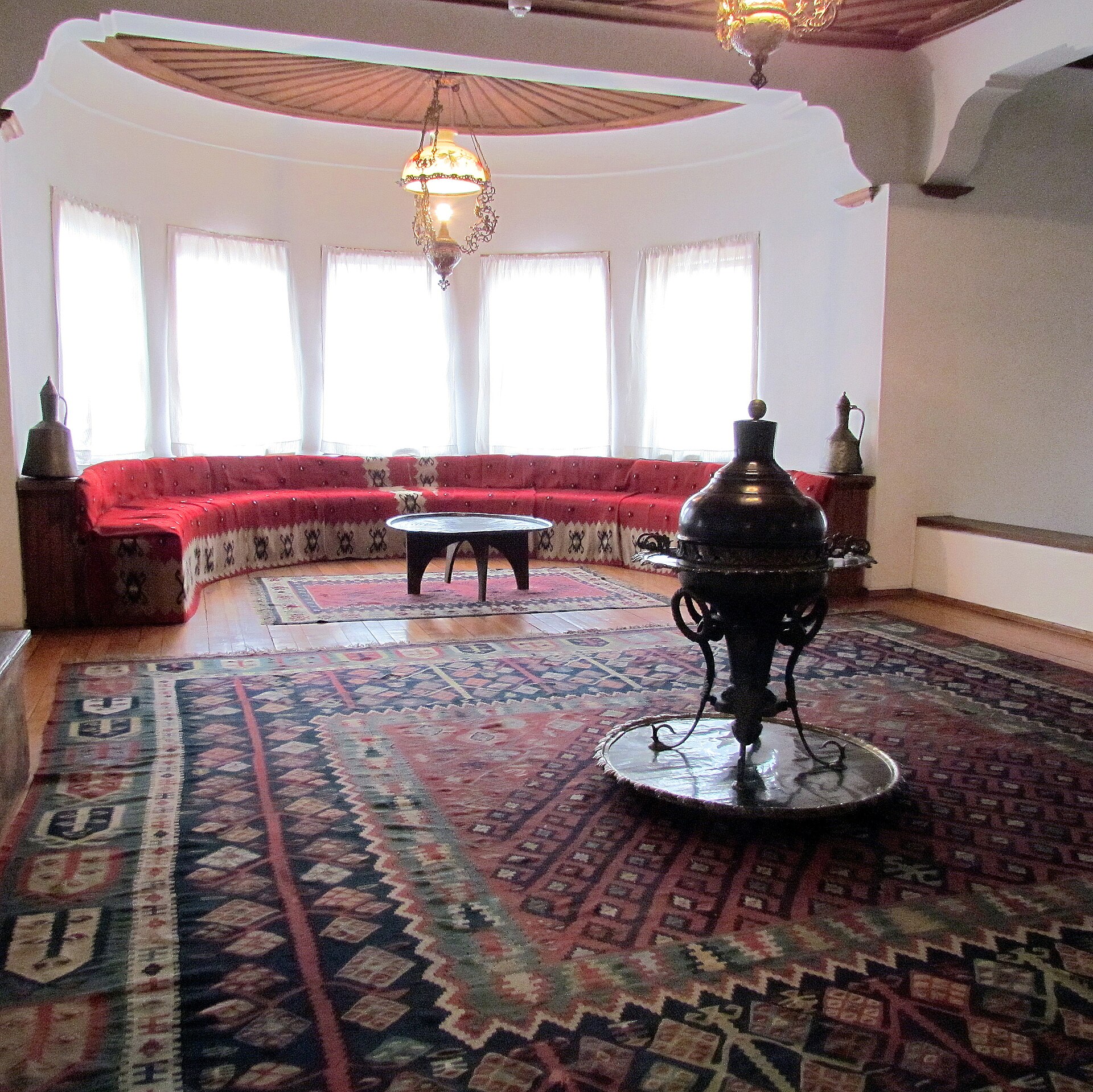The Divanhana, a bay-windowed reception room with a continuous low red divan and a central copper brazier