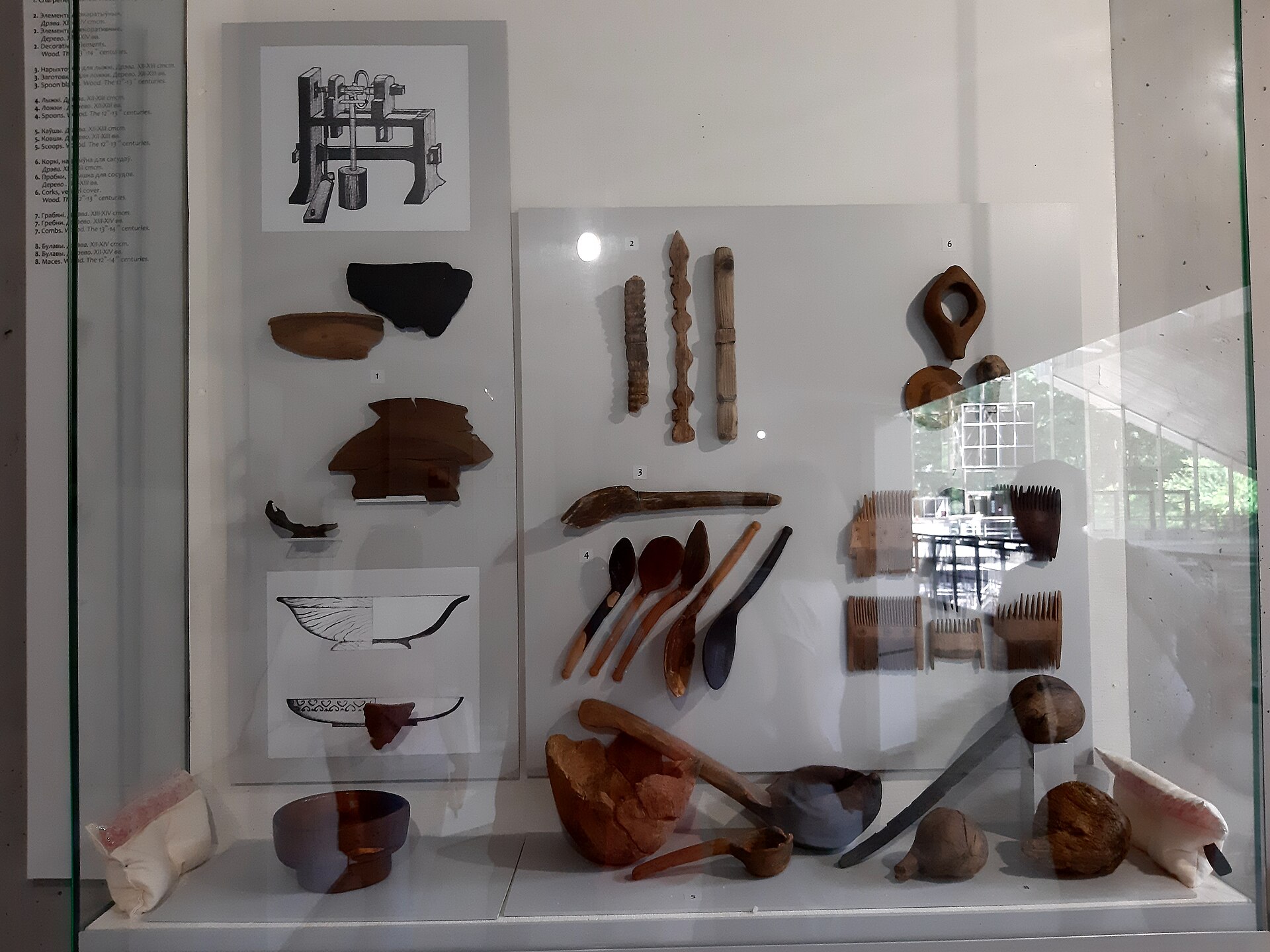 A glass display case of carved wooden spoons, bowls and turned vessels from the craft halls flanking the excavation