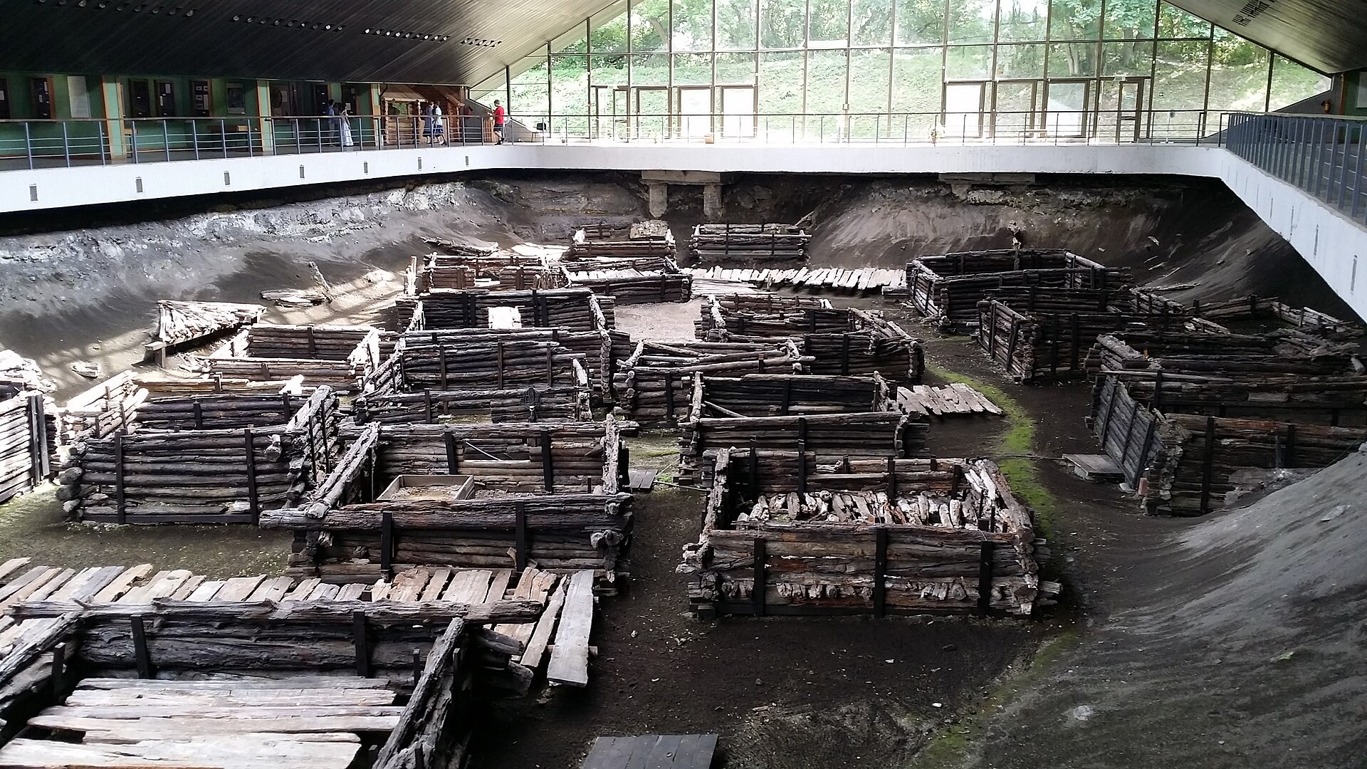Looking down from the elevated walkway at rows of excavated thirteenth-century log buildings and wood-plank streets inside the museum pavilion