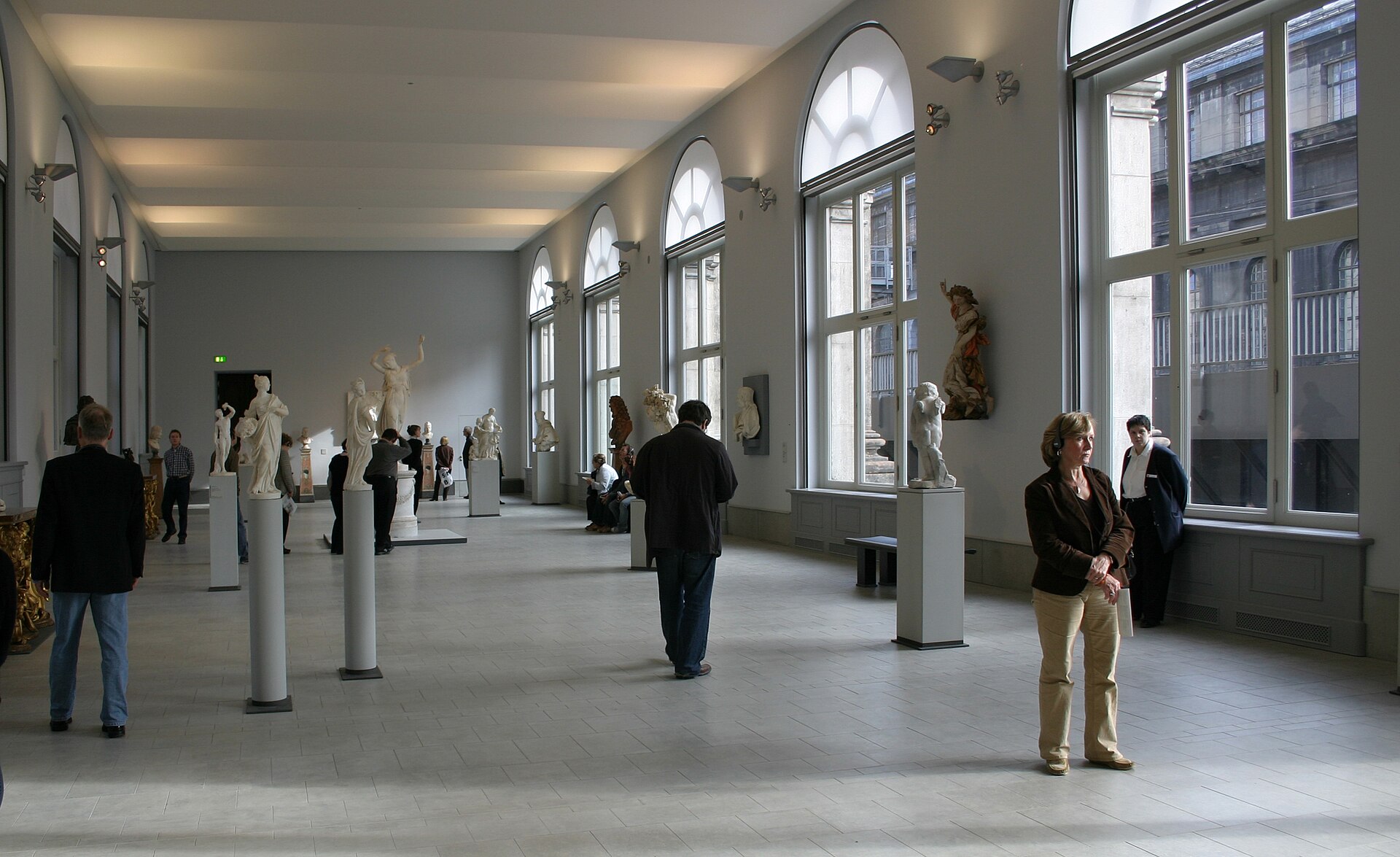 A colonnaded sculpture hall in the Bode-Museum, marble figures on plinths along a row of arched windows