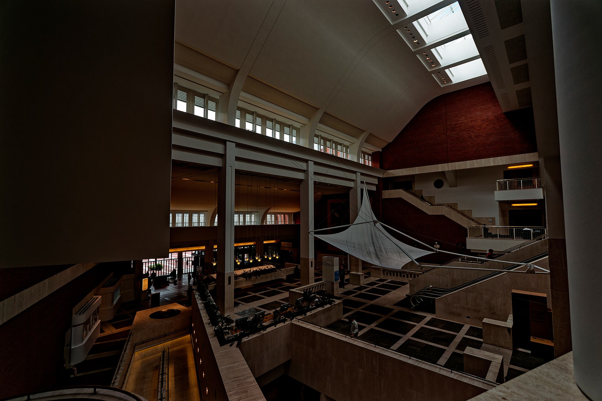 Looking down into the Entrance Hall from a gallery level: escalators, staircases and a stretched fabric canopy beneath the roof skylights