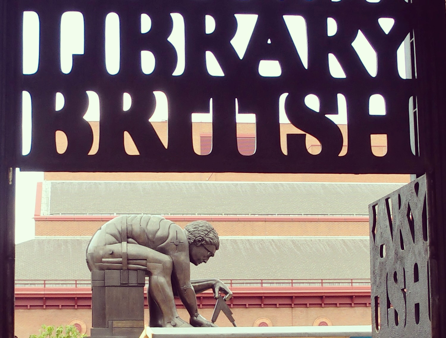Paolozzi's bronze Newton, stooped over a pair of compasses, framed through the cut-out BRITISH LIBRARY lettering of the piazza gate with the red-brick facade behind