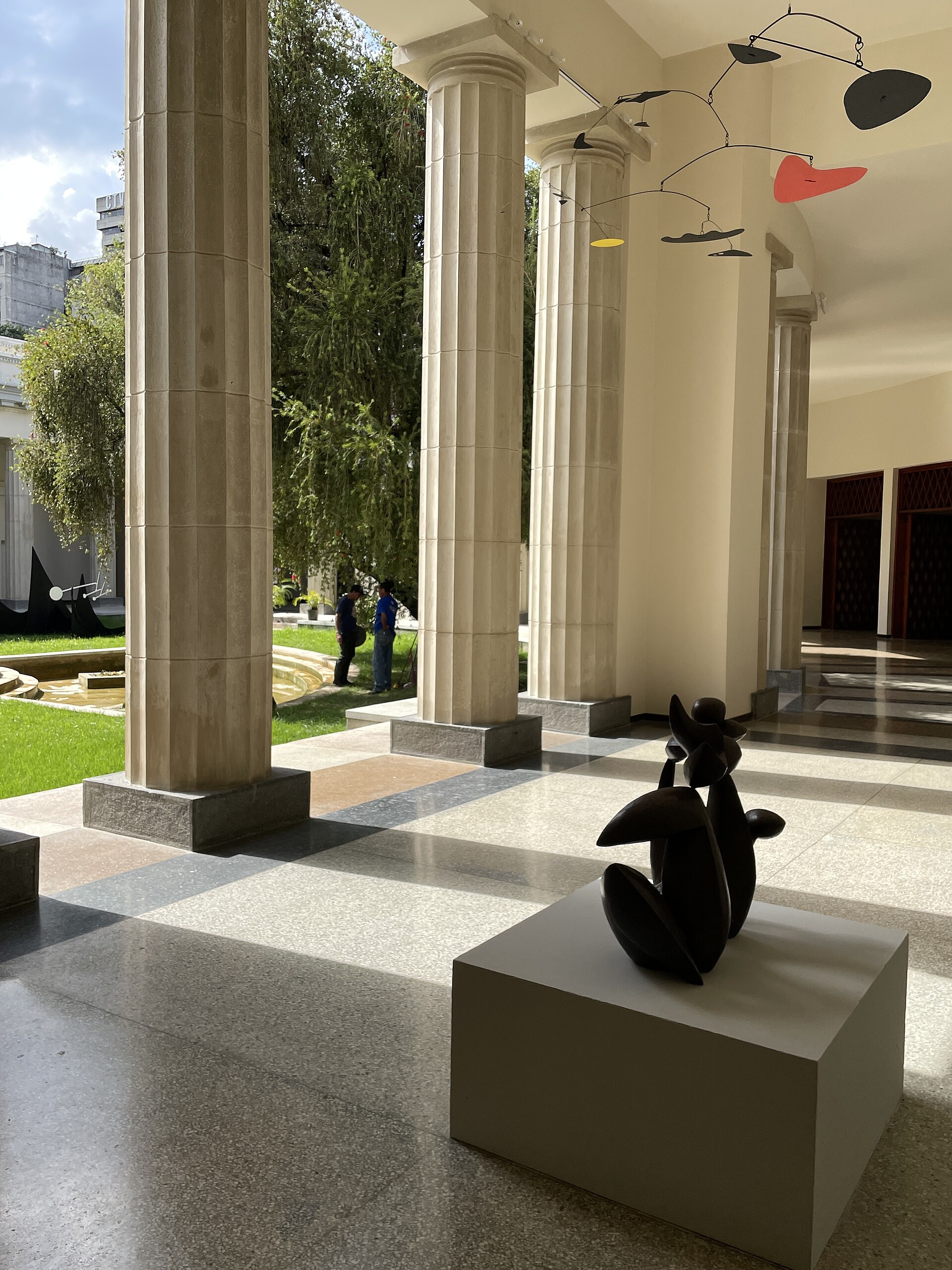 Colonnaded portico of the neoclassical building, looking out toward the museum's central patio, with a Calder mobile and a bronze sculpture in the foreground