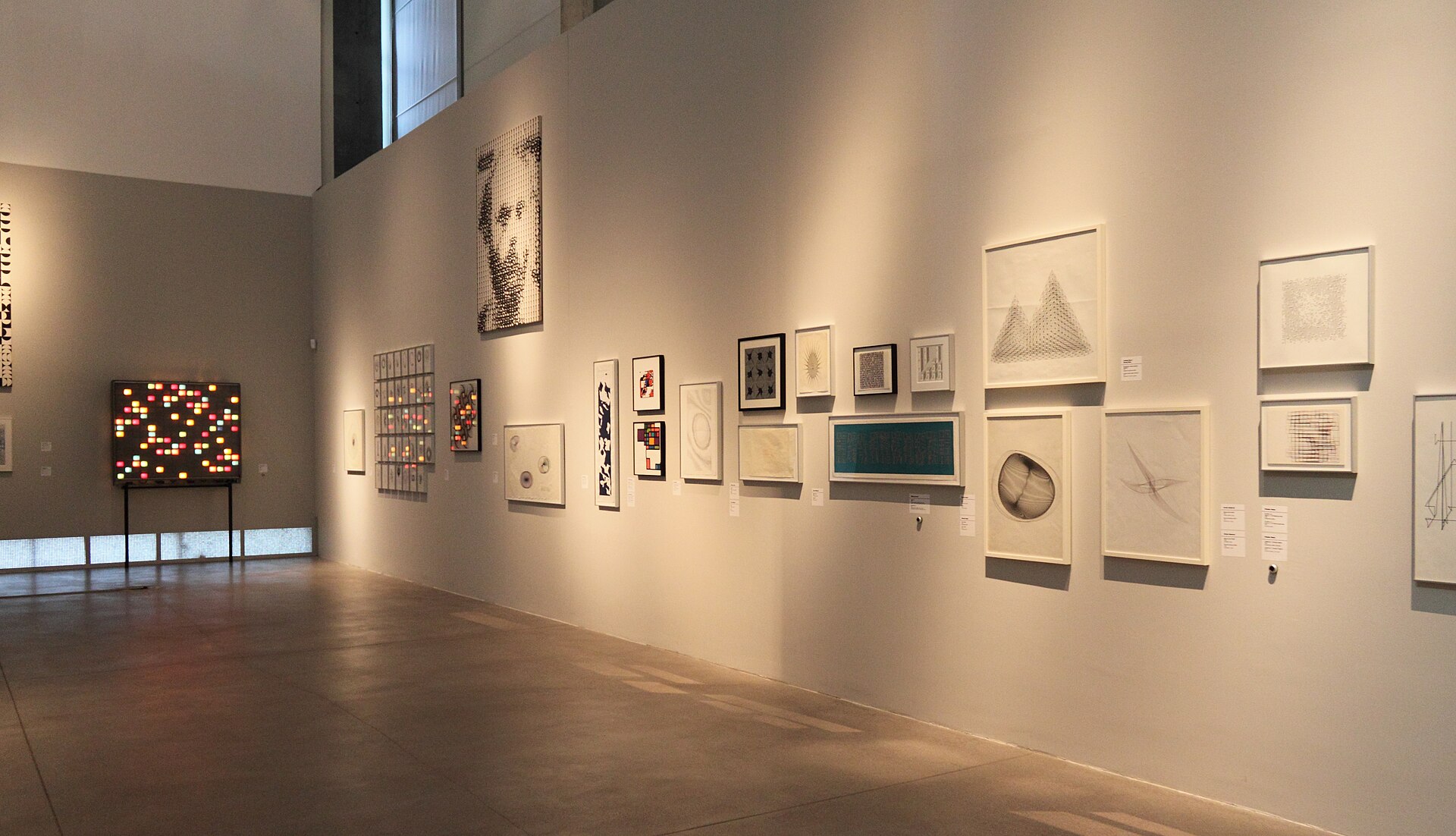 A gallery wall hung salon-style with small framed drawings and prints in varied formats