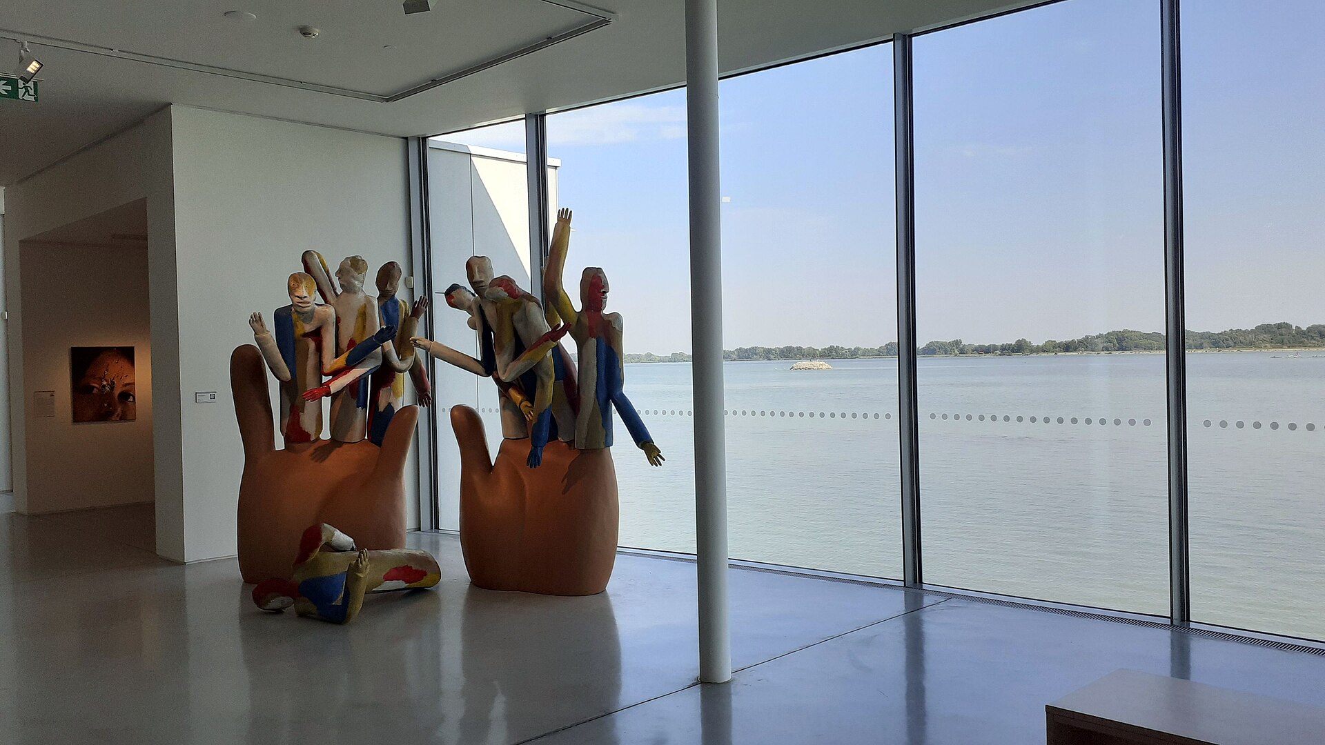 Left and Right (Lavica a pravica) by Jozef Jankovic in the sculpture park: two oversized painted hands cradling a crowd of small painted figures, with the Danube behind.