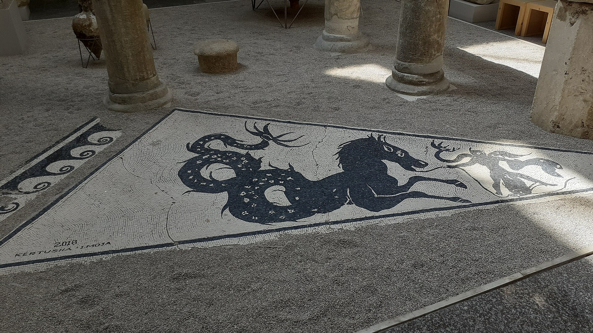 A black and white Roman mosaic panel depicting a sea monster, set into the museum floor