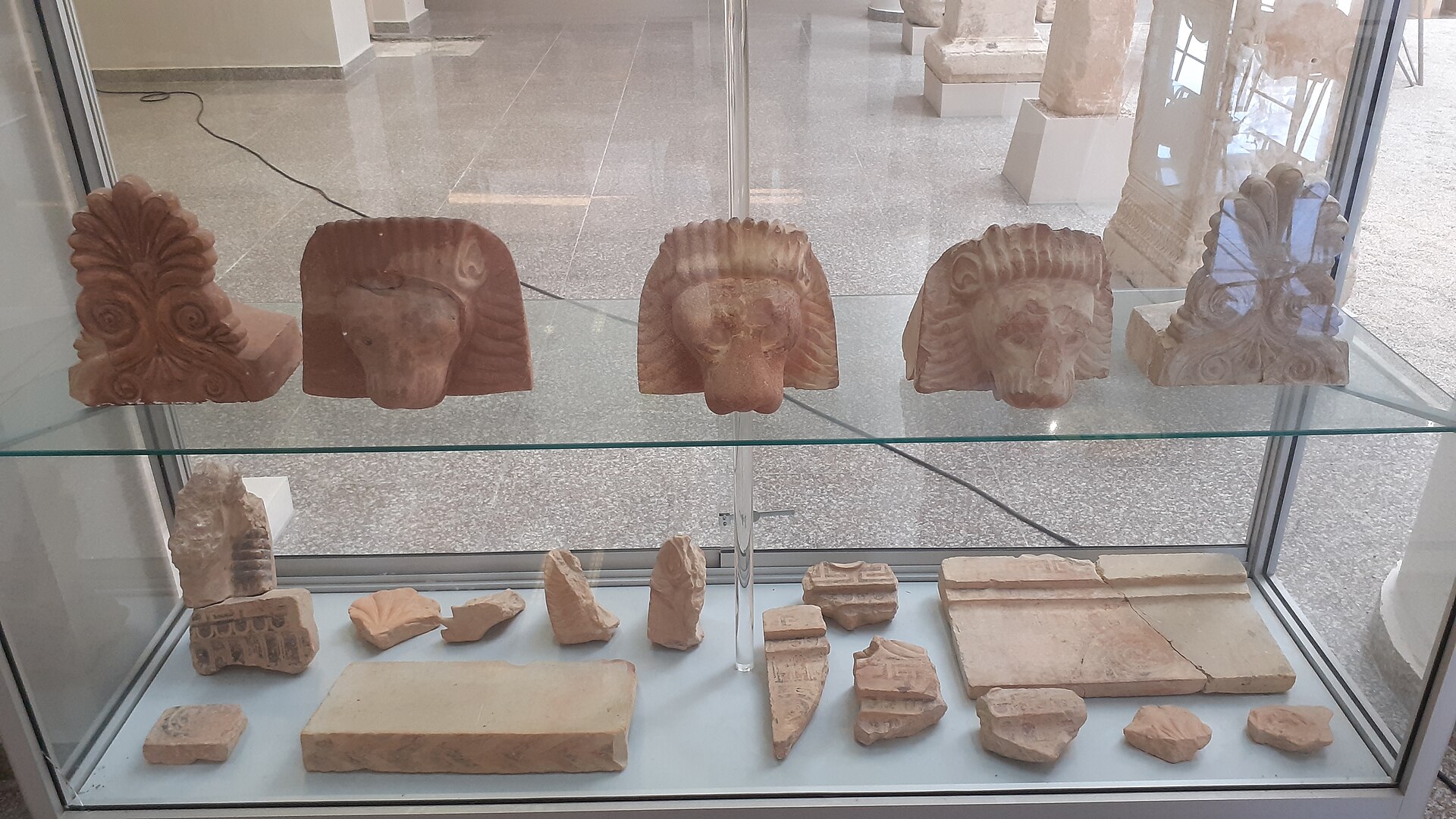 A display case of terracotta architectural antefixes and small stone and clay fragments