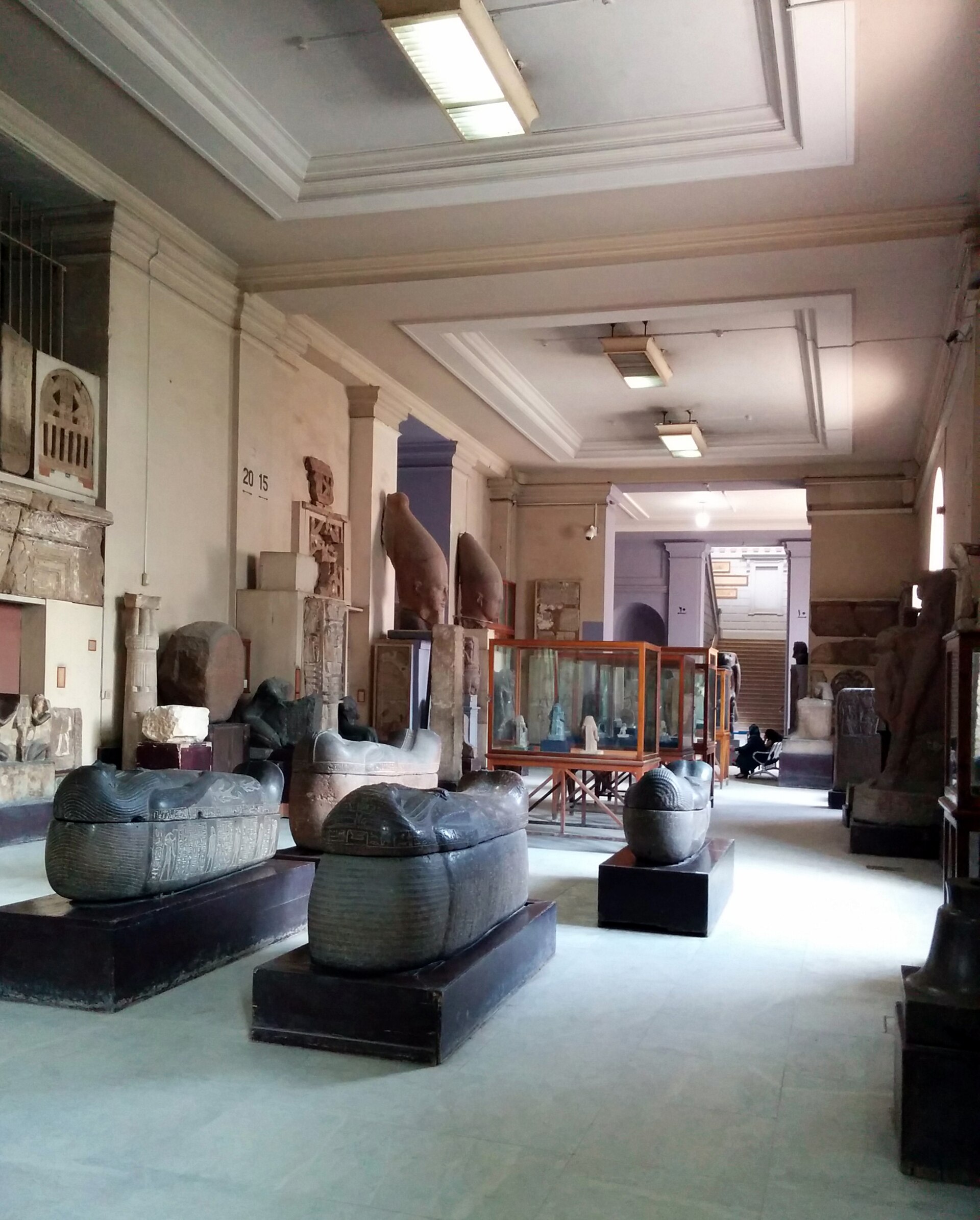 A ground-floor gallery with stone anthropoid coffins on plinths and stelae along the walls