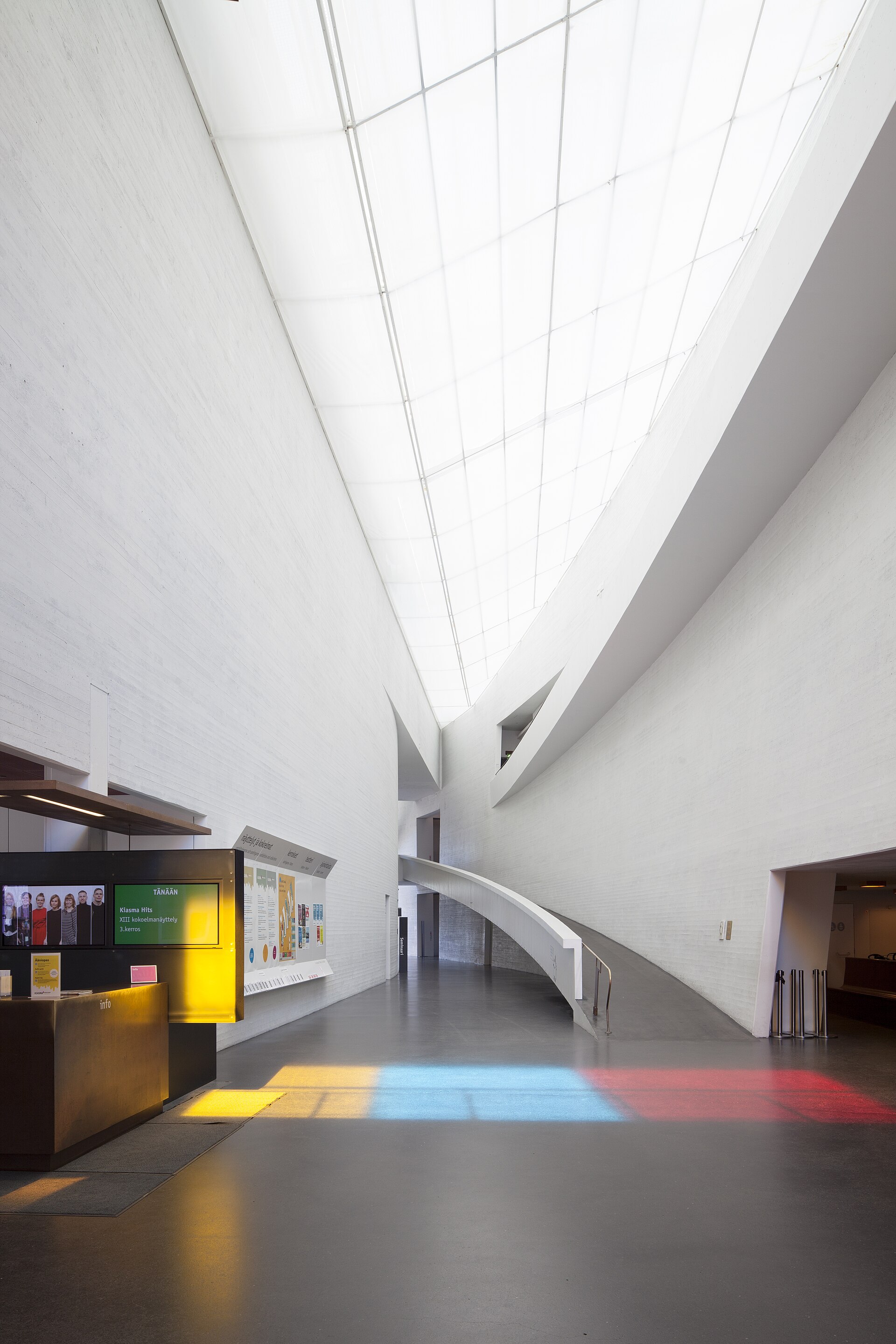 The curved concrete lobby of Kiasma, lit from a long overhead skylight, with a ramp curving down to the ground floor