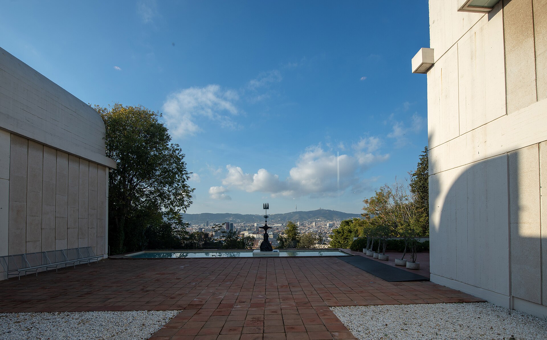 The rooftop terrace with a reflecting pool and a Miro sculpture, looking out over Barcelona toward the hills