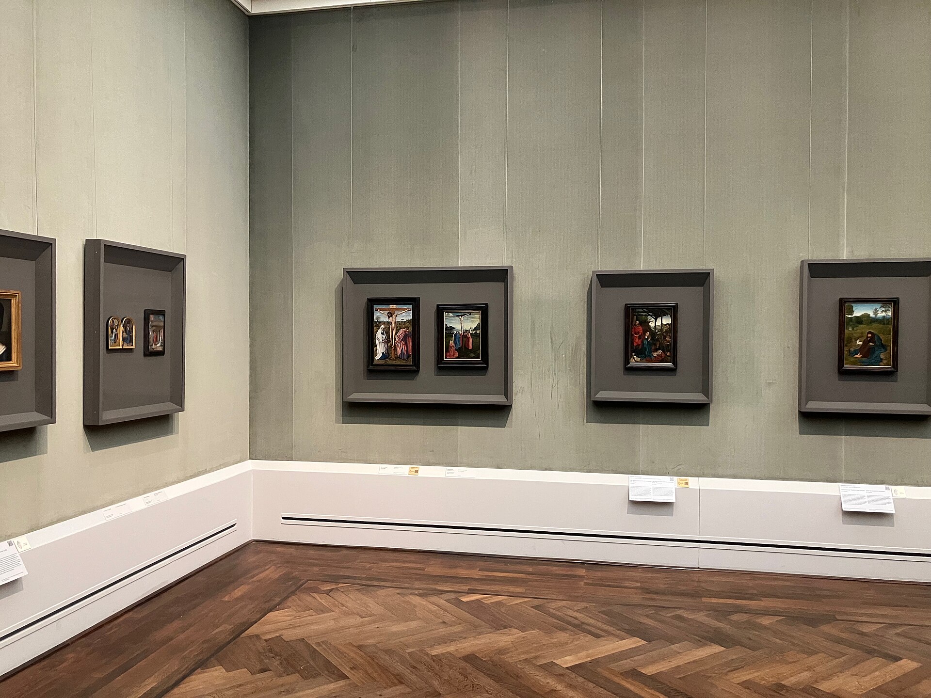 Small German panels in glazed shadow boxes on a green fabric wall