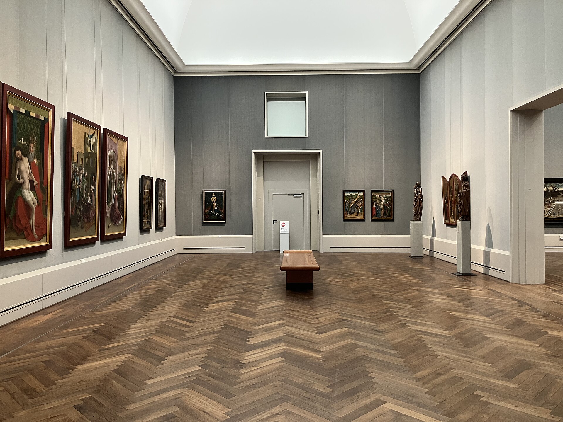 A top-lit hall of German panel painting with sculpture on plinths