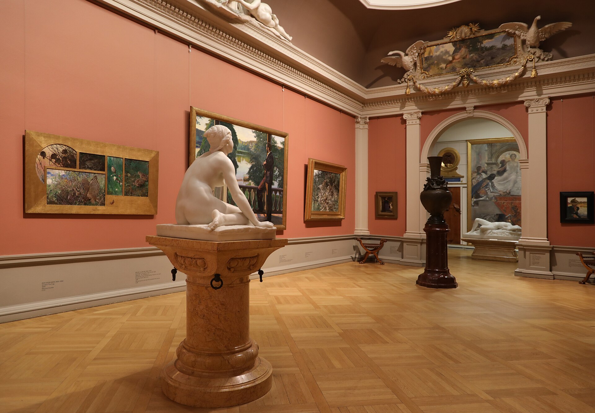 A gallery room with deep red walls hung with paintings in gilt frames, part of the Furstenberg Gallery