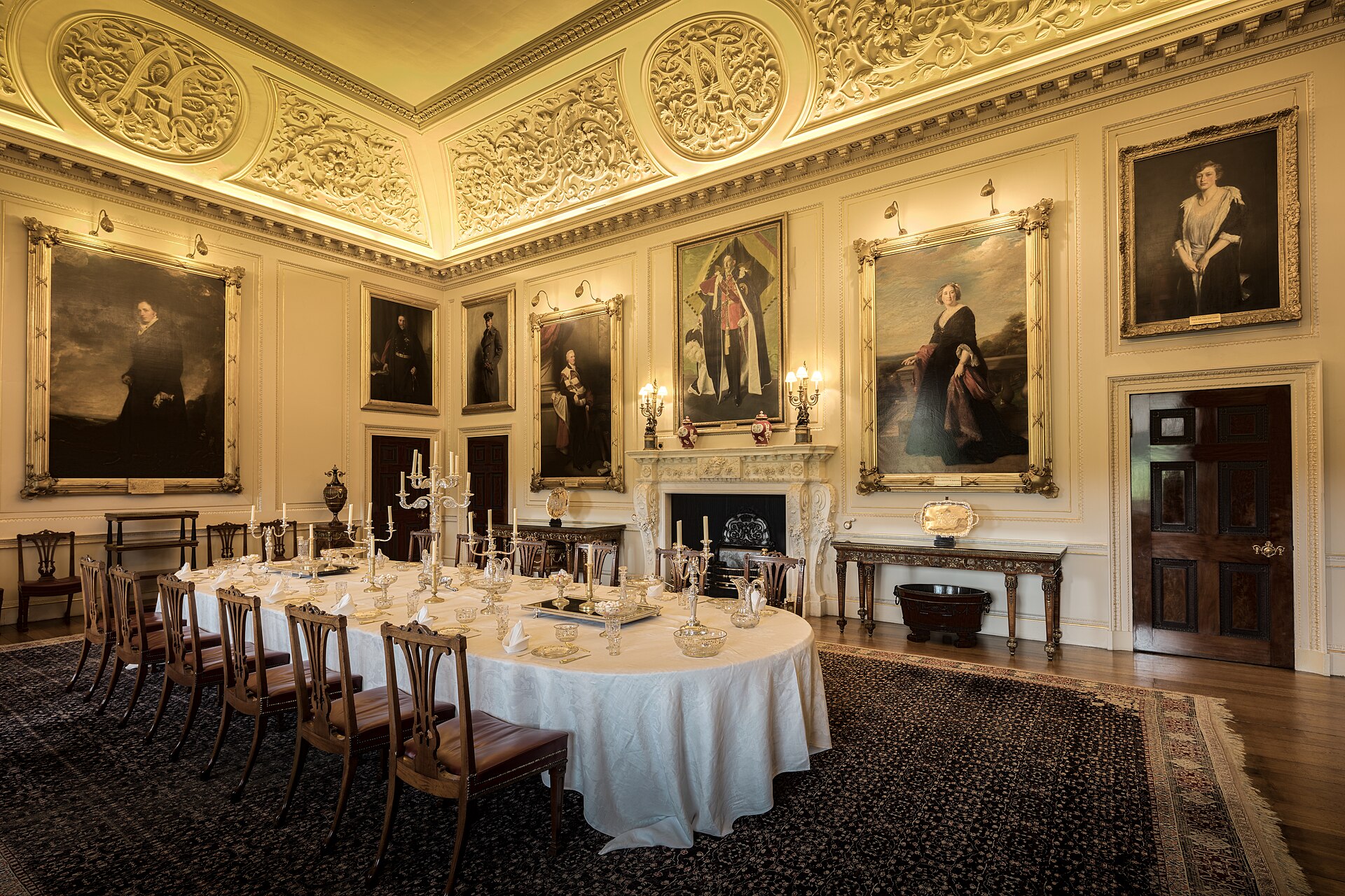 The State Dining Room laid for dinner, with the Chippendale dining suite and family portraits on the walls