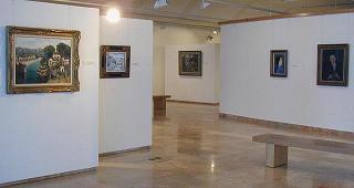 A gallery room in the Hecht Museum's art wing, framed Impressionist and Post-Impressionist paintings hung on white walls around a marble floor and a museum bench