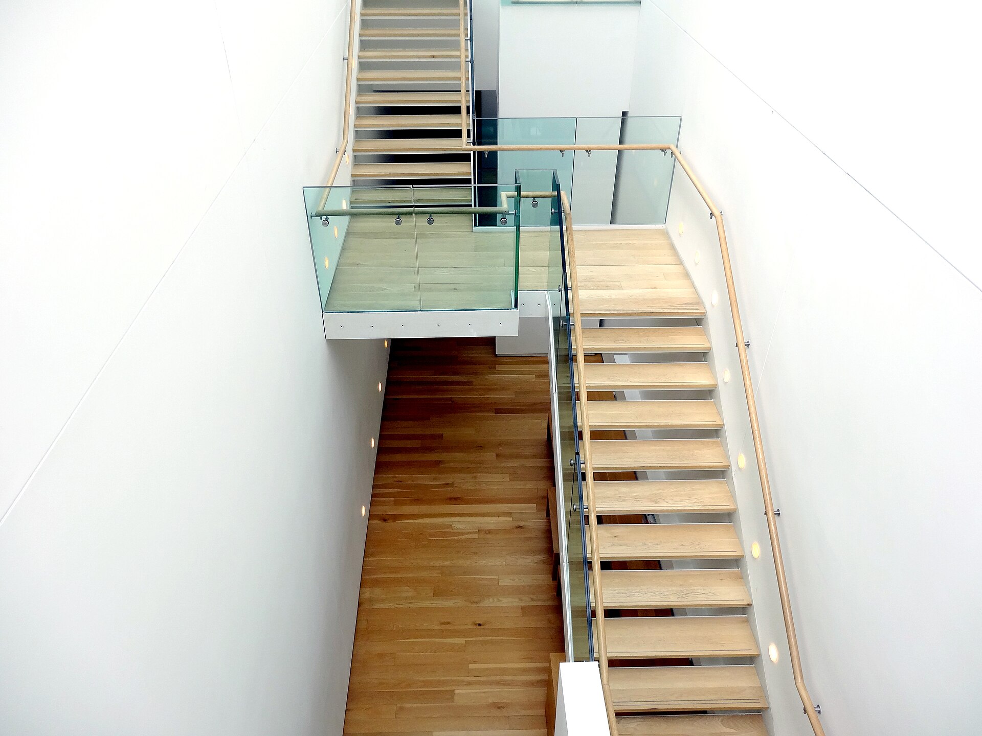 A contemporary open staircase of pale wood treads and glass balustrades inside the gallery's 2006 extension