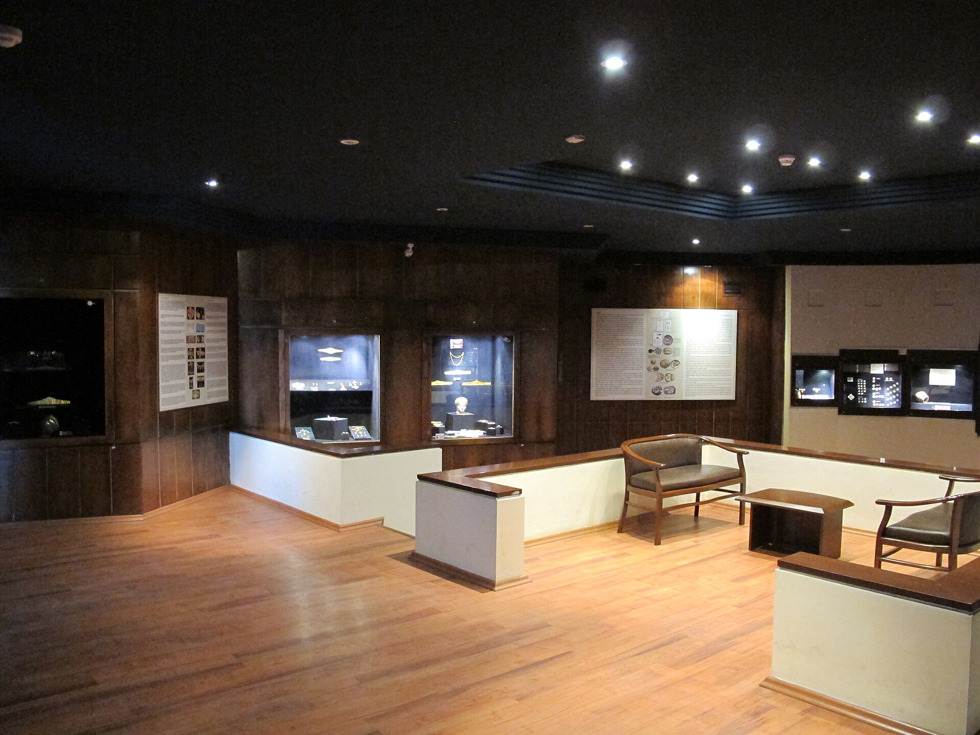 The Treasury Room, a dark wood-panelled gallery with illuminated wall cases of coins and jewellery