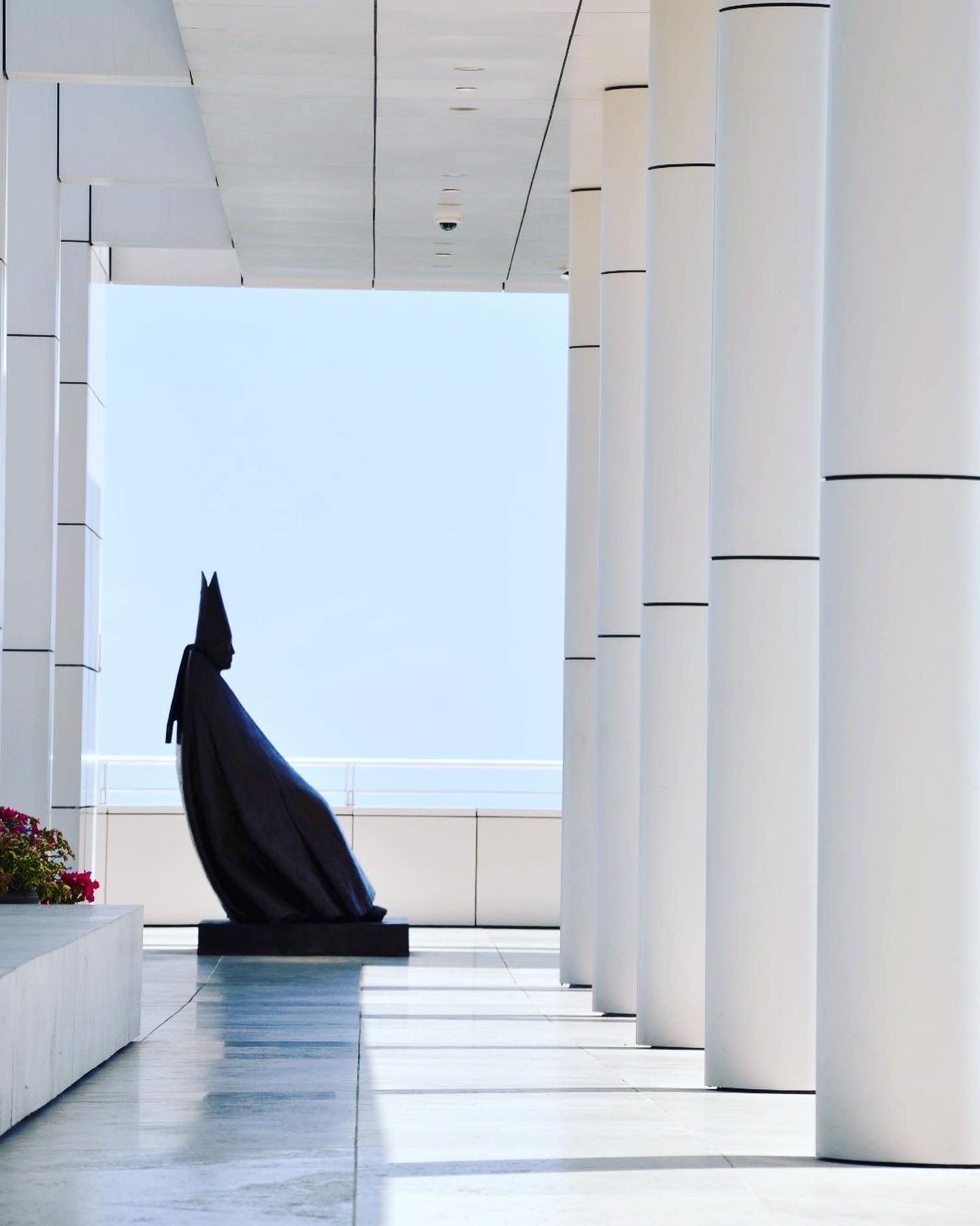 A colonnade at the Getty Center with a robed bronze figure and a view over the grounds