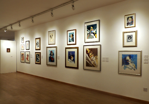 A gallery wall hung salon-style with framed clown and portrait paintings from the Permanent Collection