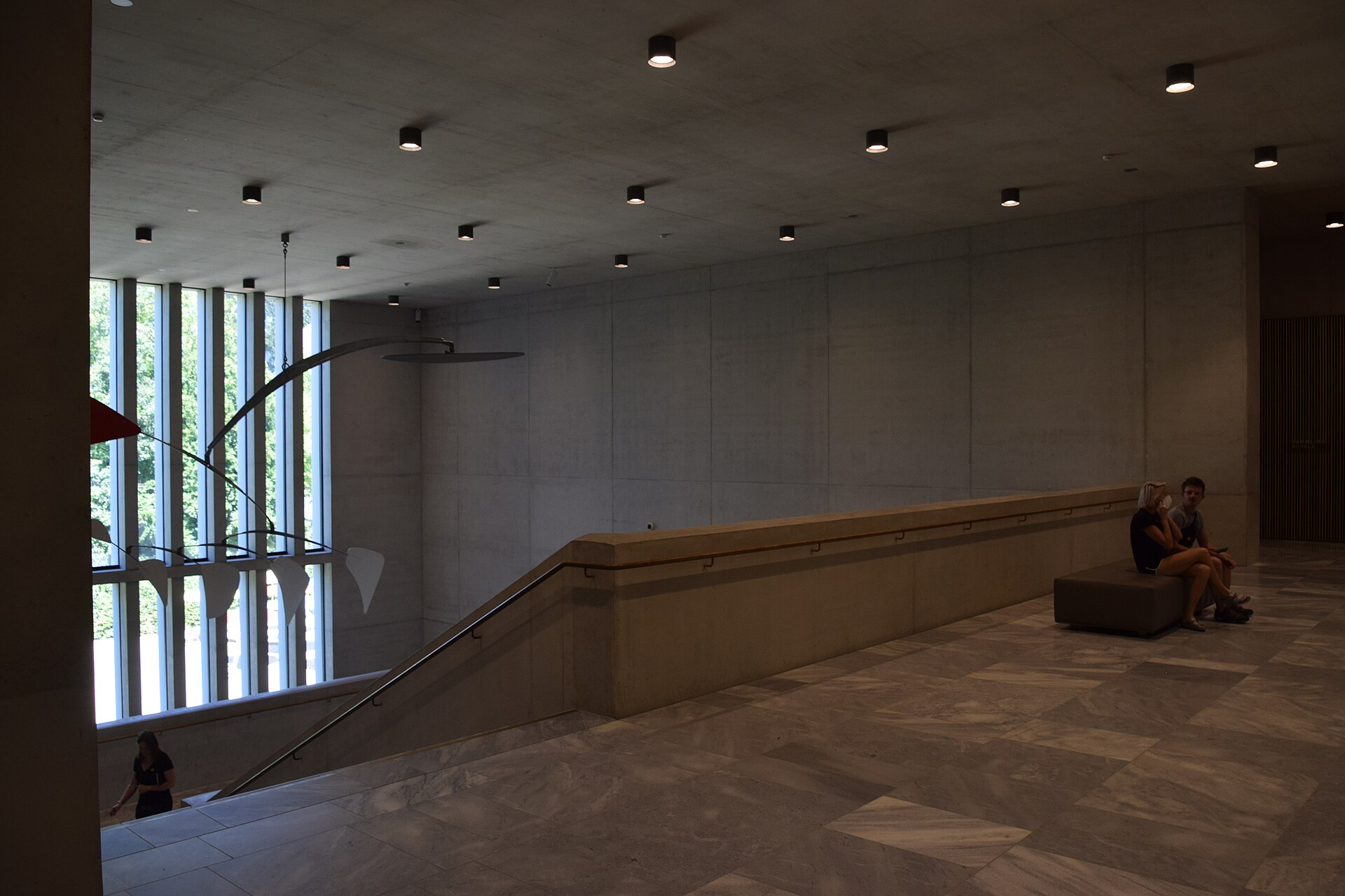 A concrete and glass stairwell inside the Kunsthaus, in the raw-concrete, tall-glazing style of the 2021 Chipperfield extension