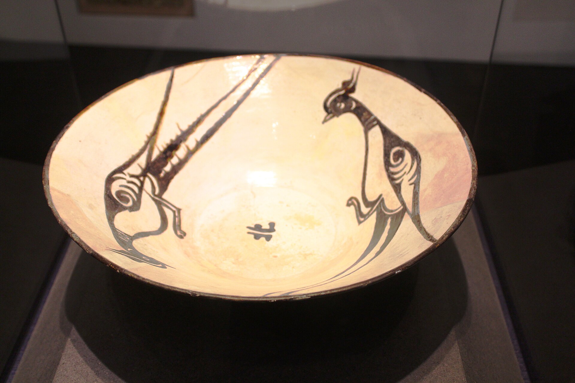 A glazed ceramic bowl painted with confronting birds, medieval Islamic pottery on display at the museum