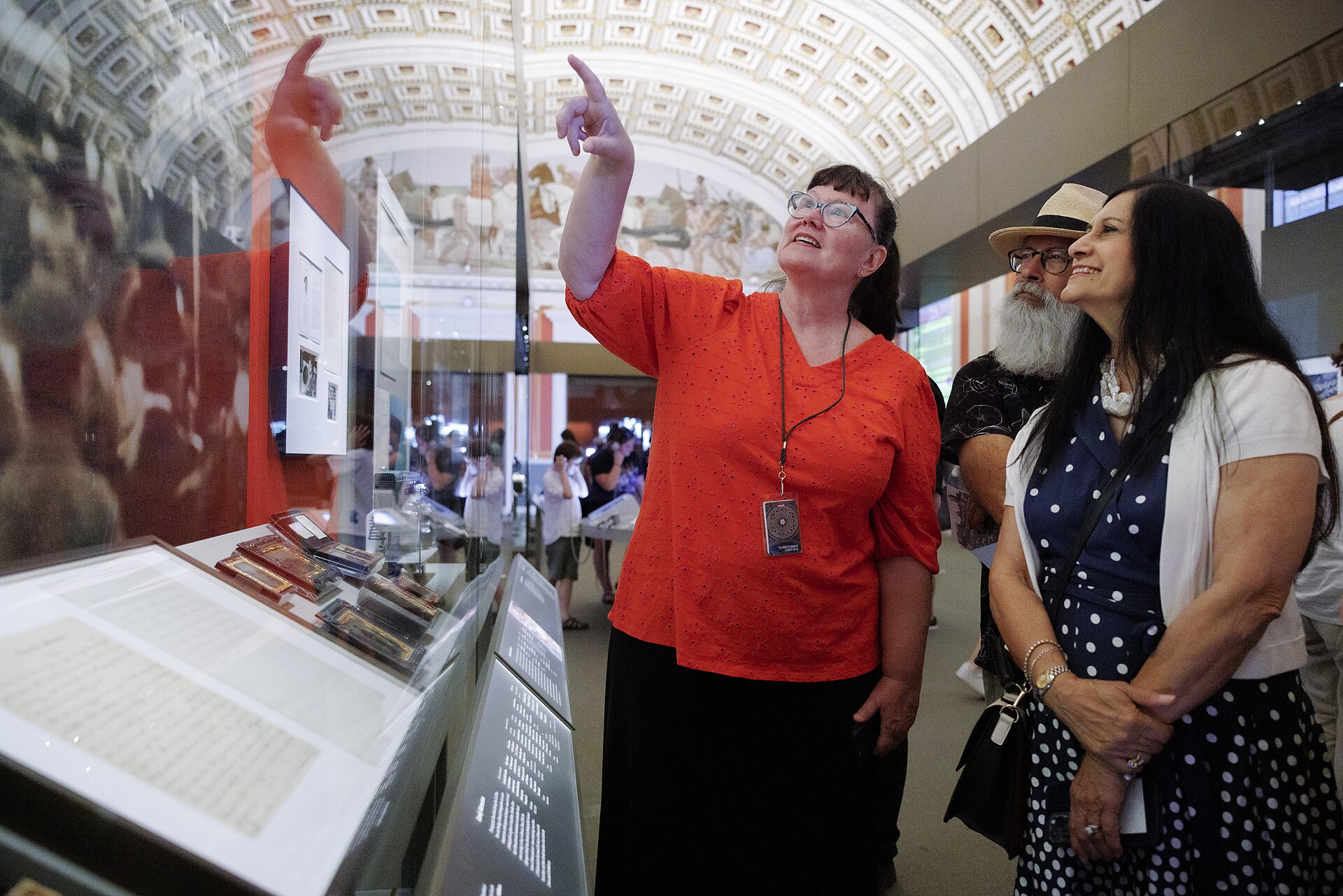 Visitors in the barrel-vaulted Treasures Gallery, looking into a low display case holding a manuscript