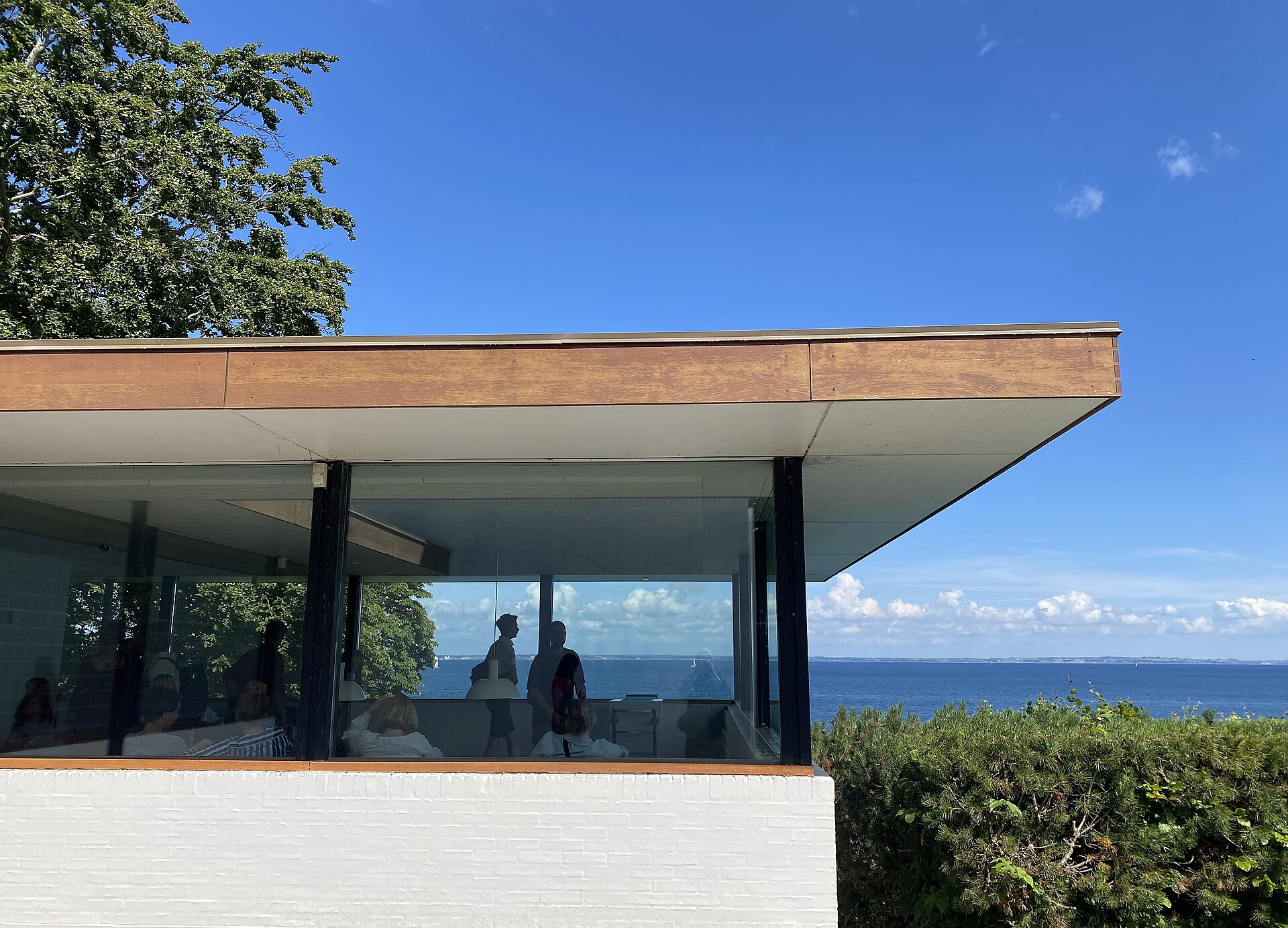 Visitors inside a glass corridor with the Oresund visible through the windows