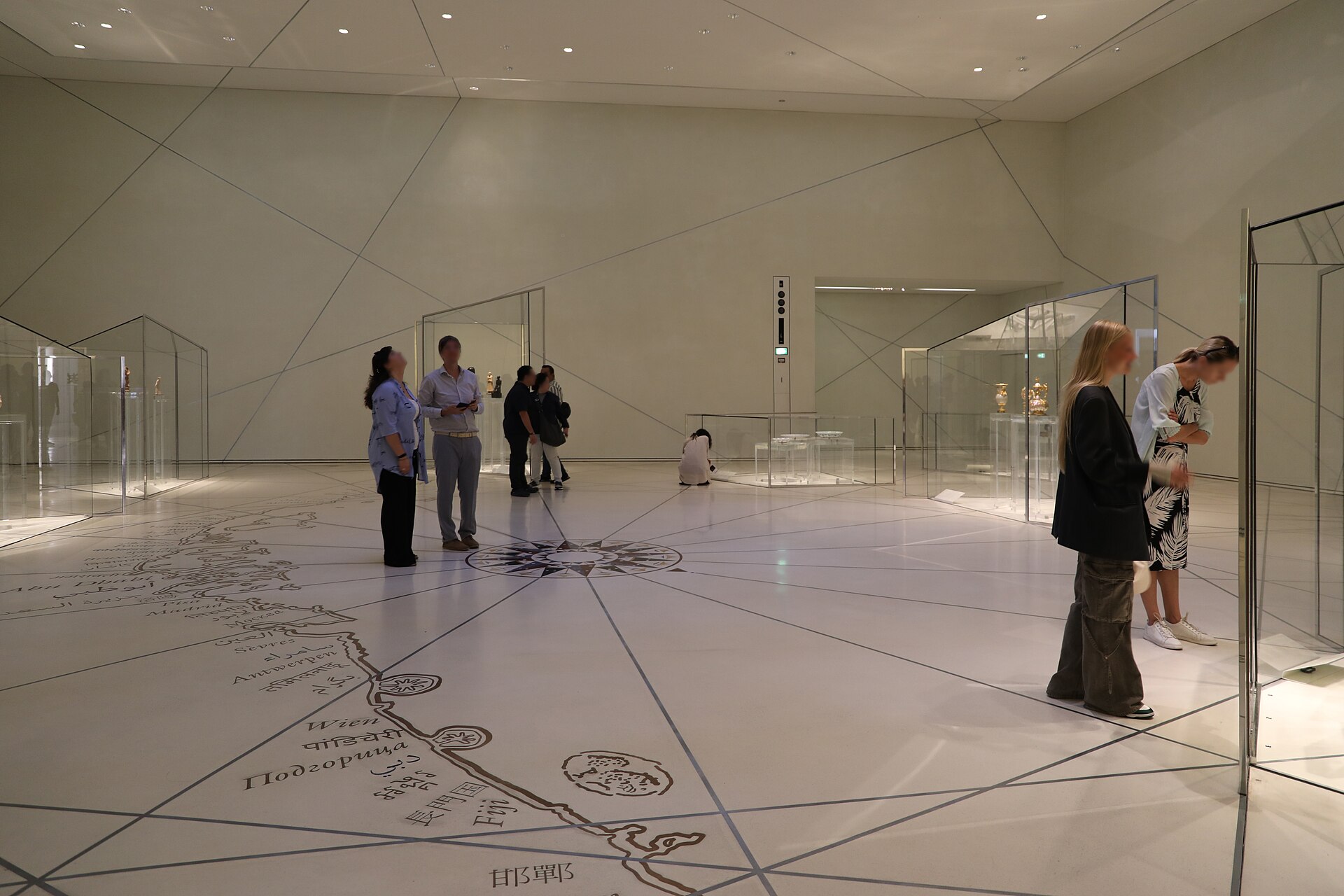 The floor of the Grand Vestibule, inlaid with a map line and visited by a small group of visitors and museum cases