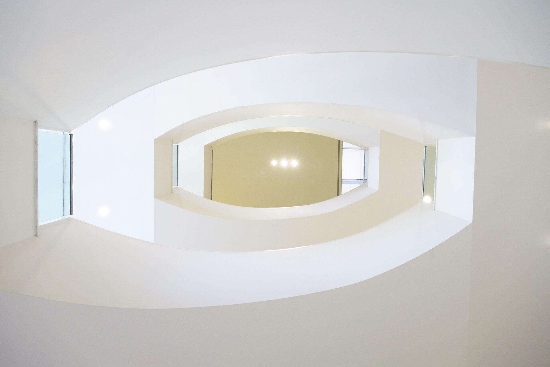The curved white stairwell of the Ludwig Museum, lit from an overhead skylight