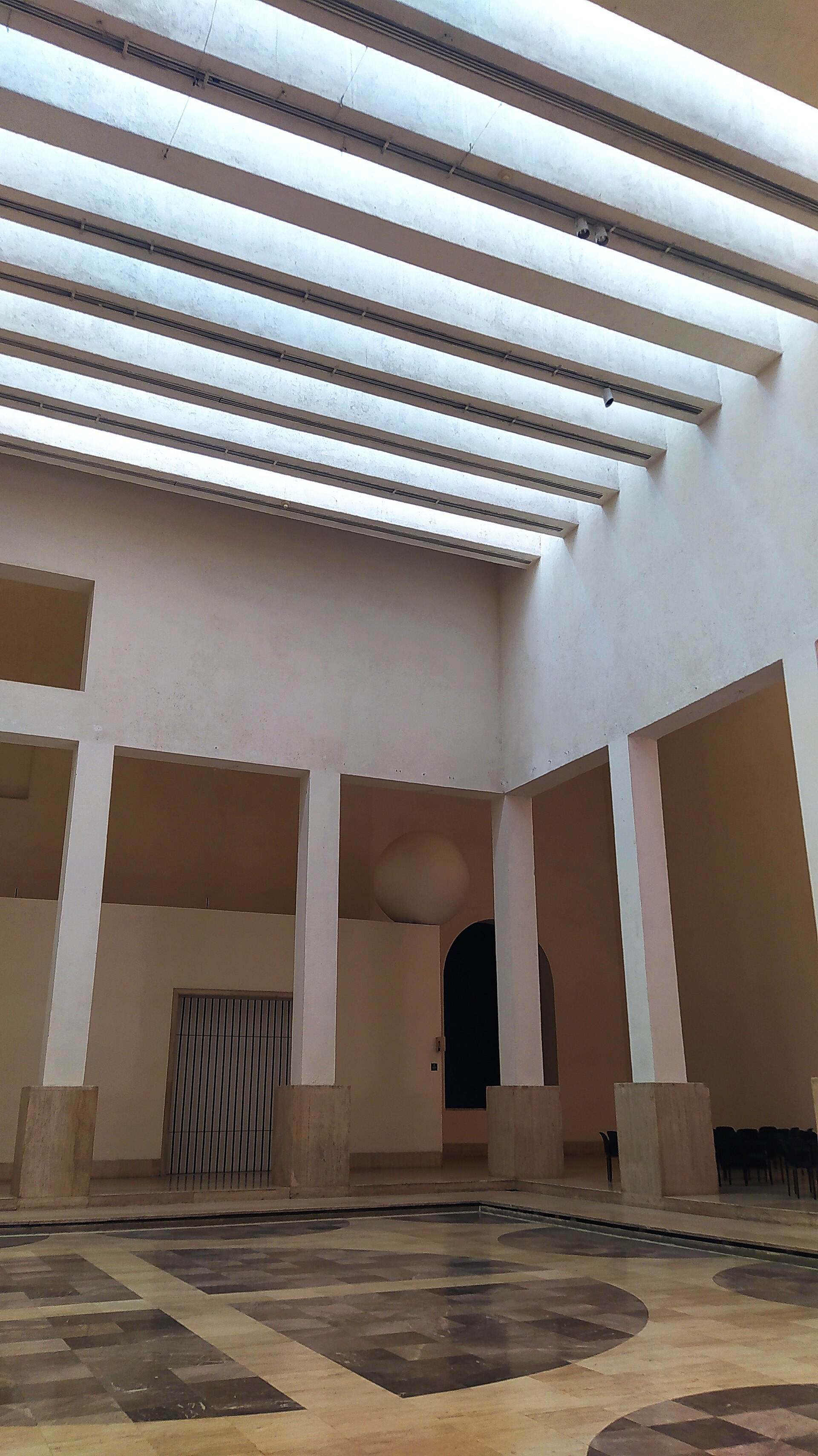 Looking up through the central courtyard's terracotta walls and ribbed skylight toward the gallery levels above