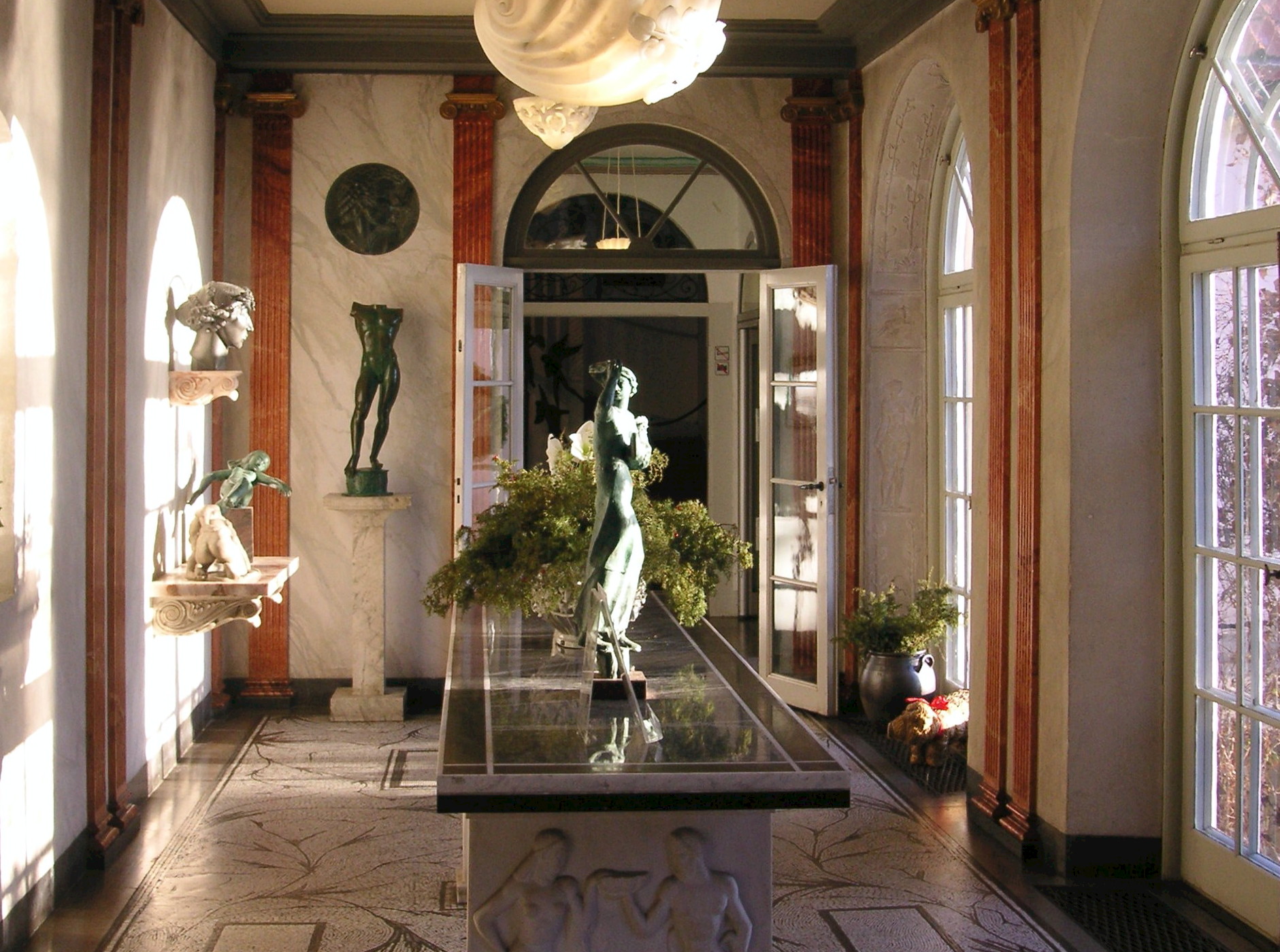 A marble-columned interior corridor in the Milles house, with bronze sculptures on plinths