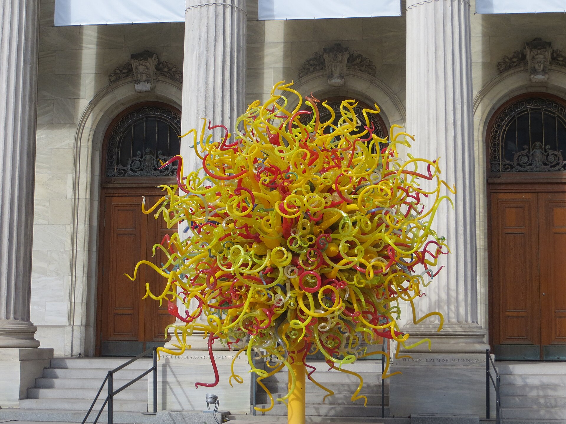 The same facade with a Chihuly glass sculpture on the steps
