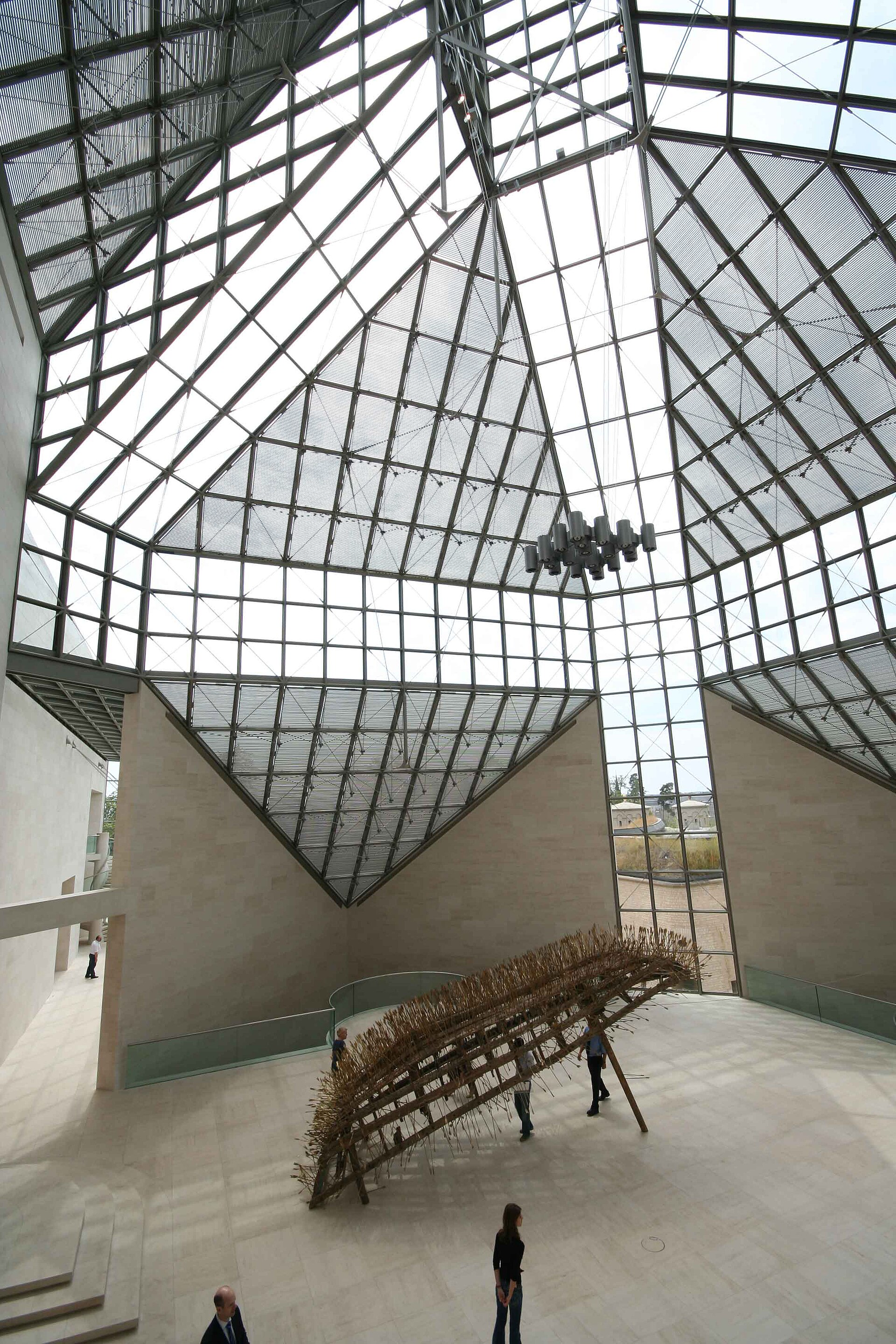 The double-height entrance hall of Mudam, lit by a glazed pyramidal skylight above pale stone walls