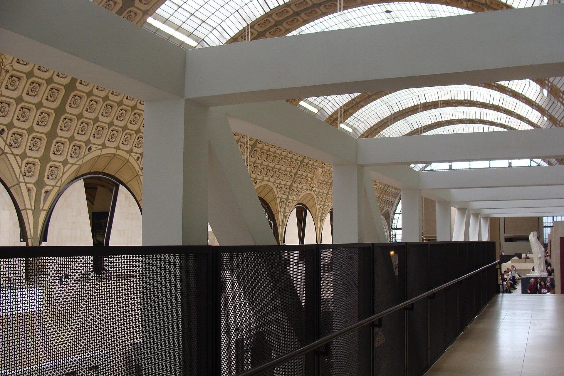 A middle-level terrace walkway overlooking the nave, with sculpture visible on the floor below