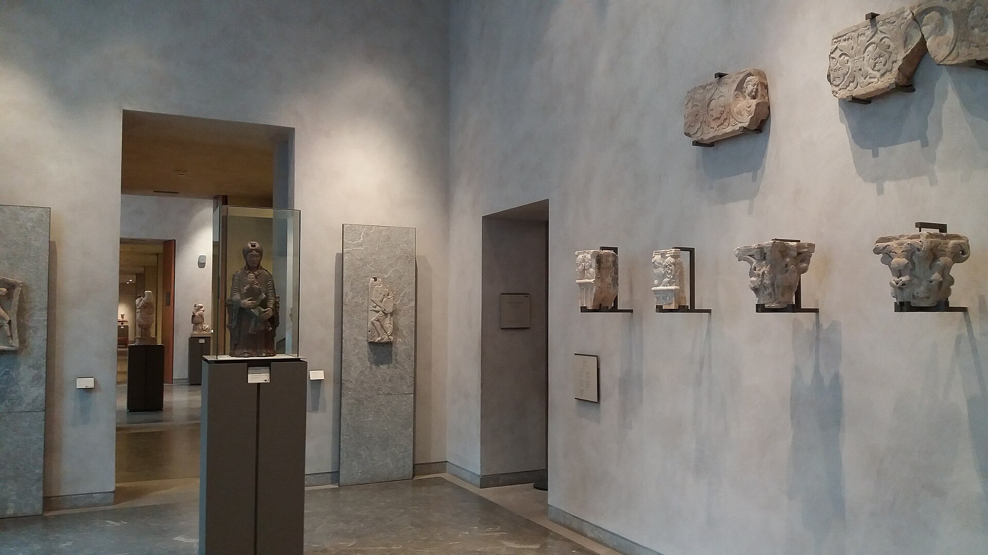 A room of carved Romanesque capitals and stone fragments mounted on the walls and on pedestals.