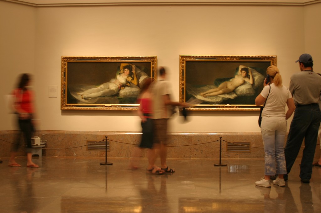 Goya's two Majas hanging side by side on a plain wall, with visitors passing in front