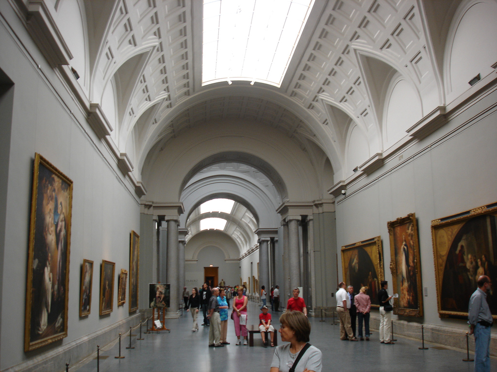 The long barrel-vaulted central gallery, top-lit, with paired grey columns dividing the bays and large paintings on both walls