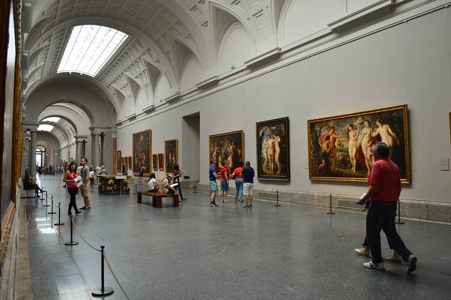A vaulted top-lit gallery hung with large Rubens canvases including the Three Graces, visitors gathered before them