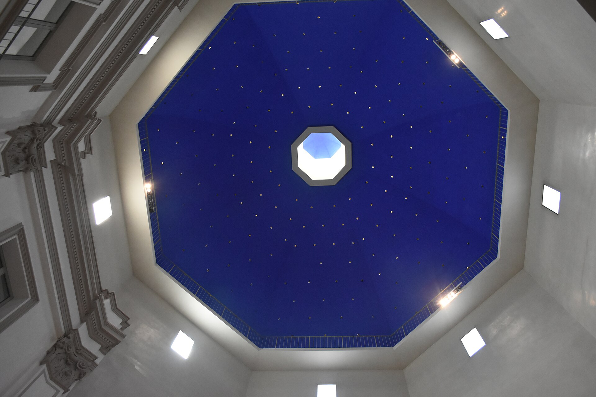Looking straight up into an octagonal domed ceiling painted deep blue and scattered with small light points around a central lantern opening