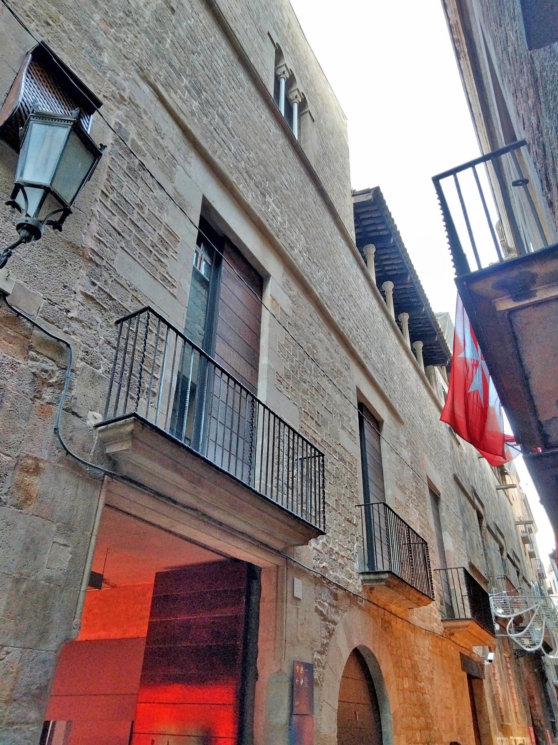The street facade of Palau Finestres on Carrer de Montcada, with a Catalan flag hanging beside the entrance