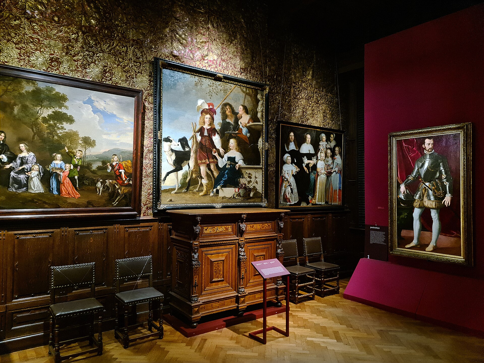 A gallery with gilt leather wall coverings hung with seventeenth-century family and individual portraits above carved oak furniture