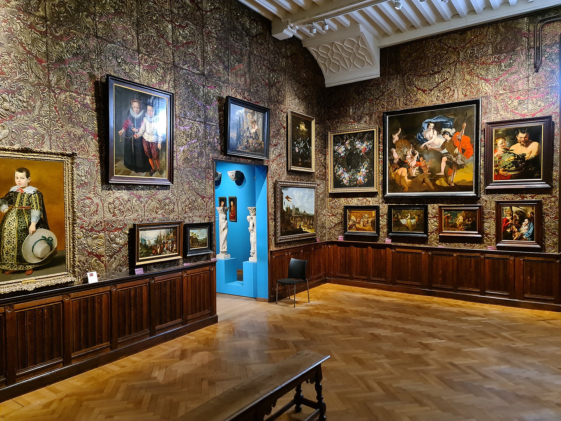 A vaulted gallery combining paintings, carved wooden sculpture and applied art objects on wall-mounted cabinets