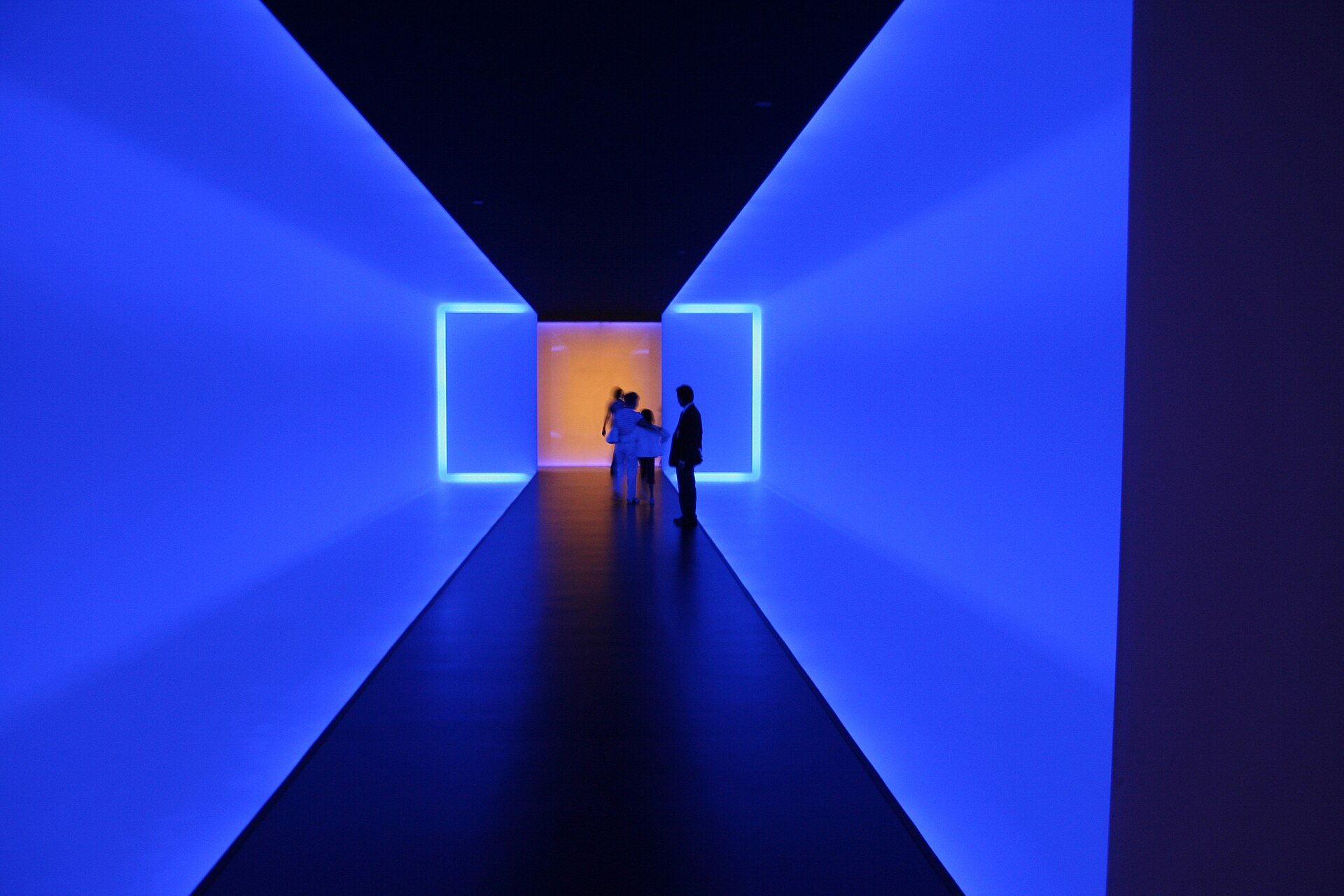 Visitors silhouetted inside James Turrell's blue-lit tunnel installation The Light Inside